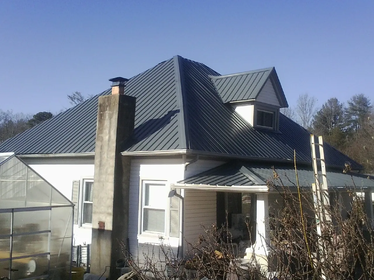 Dark blue standing seam metal roof on a white farmhouse with dormer — Slate & Tile Roof Repair by Roofing Brothers in Winder