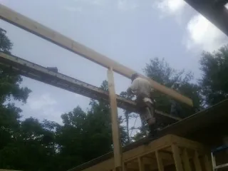 Carpenter setting a ridge beam over a new addition frame — Ice Dam Removal by Roofing Brothers in Winder