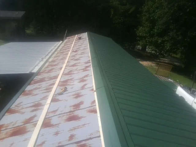 Old rusted panels beside newly installed green metal roofing — Wind Damage Roof Repair by Roofing Brothers in Winder