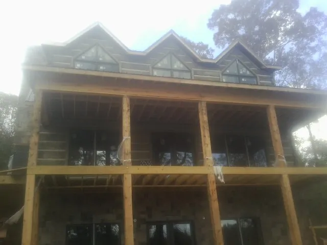 Dormers and porch framing on a large log home under construction — Roof Coating work by our crew in Winder