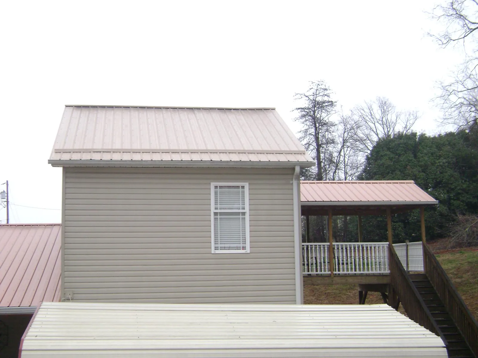 Tan metal roofs on a two story addition and attached porch, from a Roof Replacement job in Winder