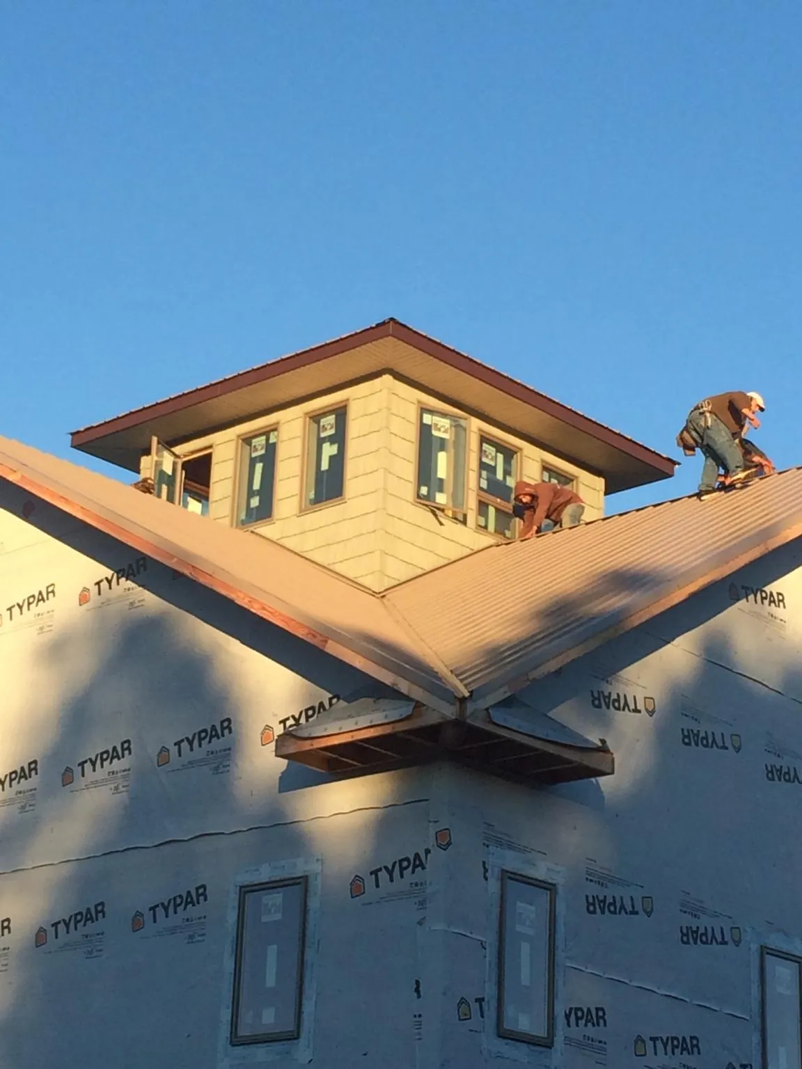 Roofers working around a rooftop cupola on a new metal roof at sunset — Roof Waterproofing in Winder by Roofing Brothers